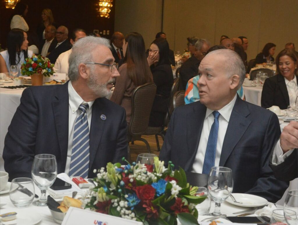 Representantes de la UNE y la DGII conversan durante el desayuno empresarial